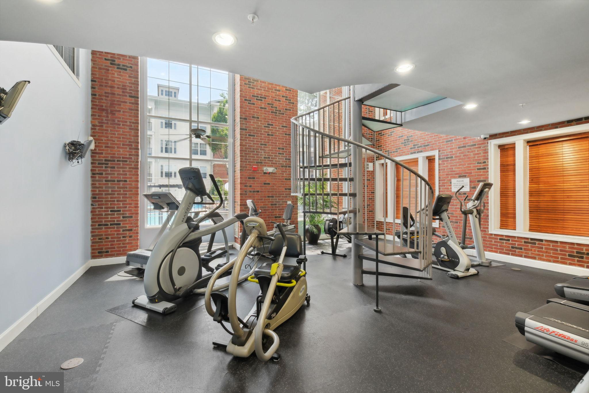 1 Arch Place, Unit 220 Gaithersburg, MD 20878 - Photo 21 of 26 Modern gym with spiral staircase and natural li...
