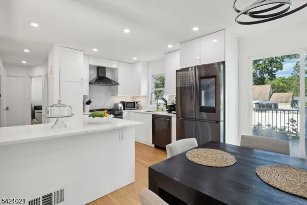 a kitchen with stainless steel appliances granite countertop a sink a stove a refrigerator cabinets a dining table and chairs