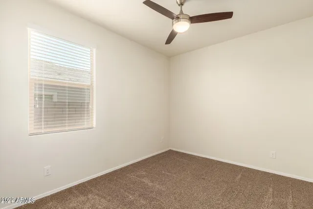 an empty room with a window and a fan