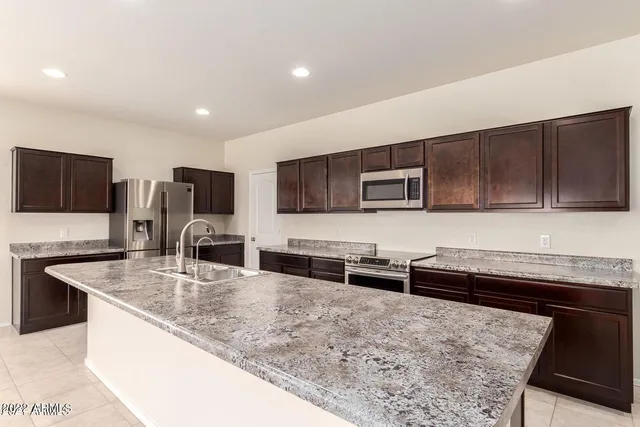 a kitchen with stainless steel appliances granite countertop a sink a stove top oven a refrigerator and dishwasher