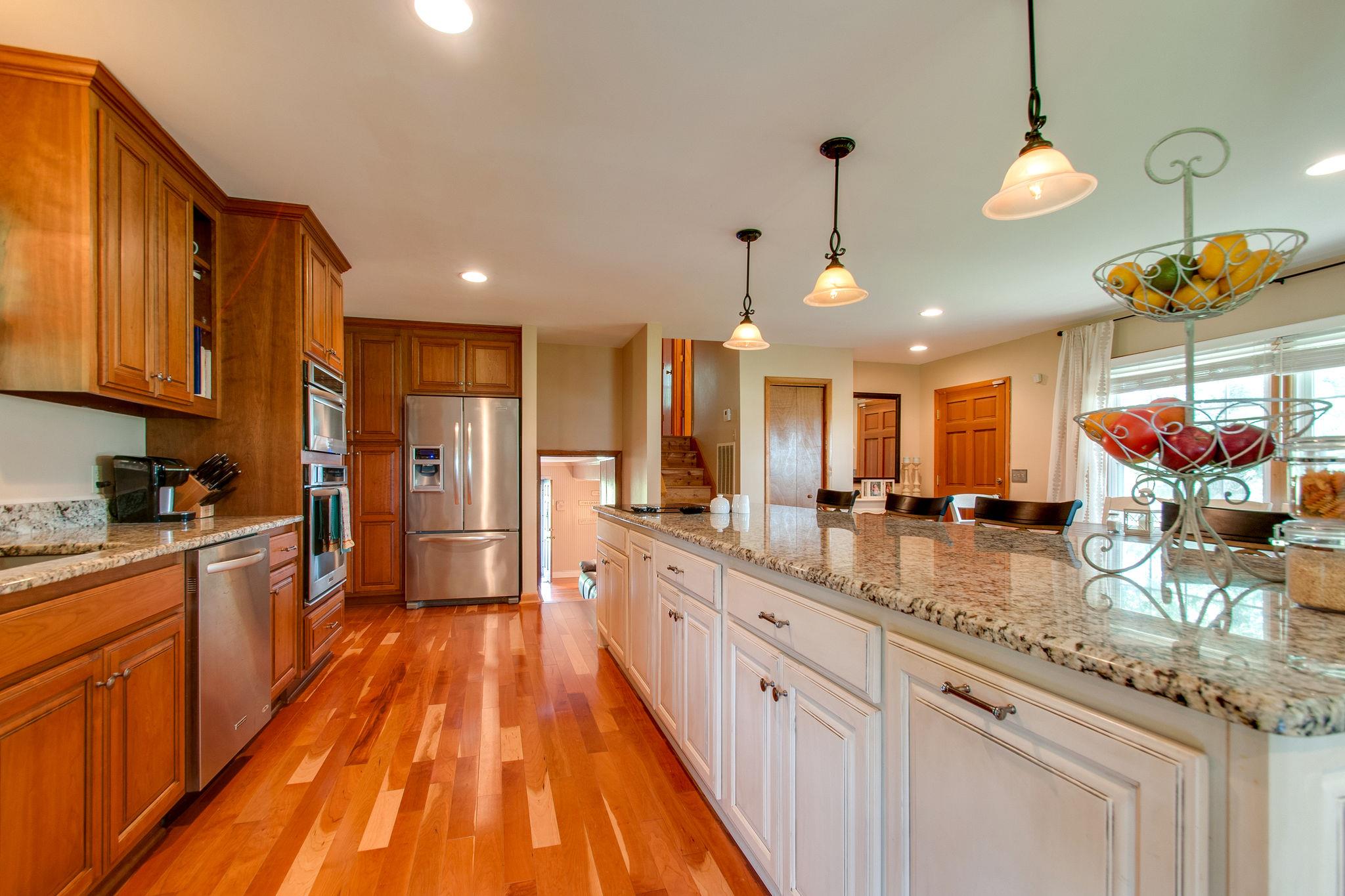 9576 Mullens Road Arrington, TN 37014 - Photo 6 of 26 a view of a kitchen with kitchen island granite countertop wooden floor stainless steel appliances and a counter space