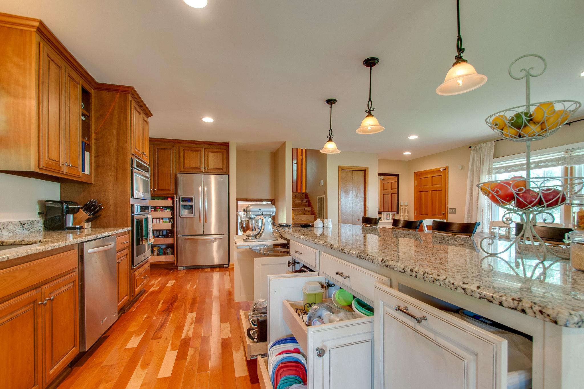 9576 Mullens Road Arrington, TN 37014 - Photo 9 of 26 a large kitchen with kitchen island granite countertop a large counter space wooden floor and stainless steel appliances