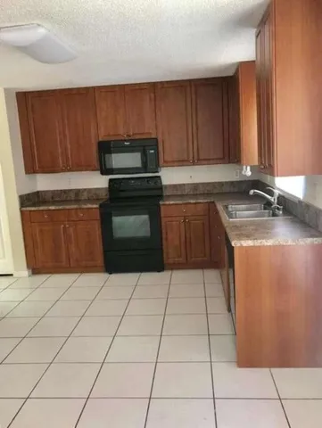 a kitchen with granite countertop a sink a stove top oven and cabinets