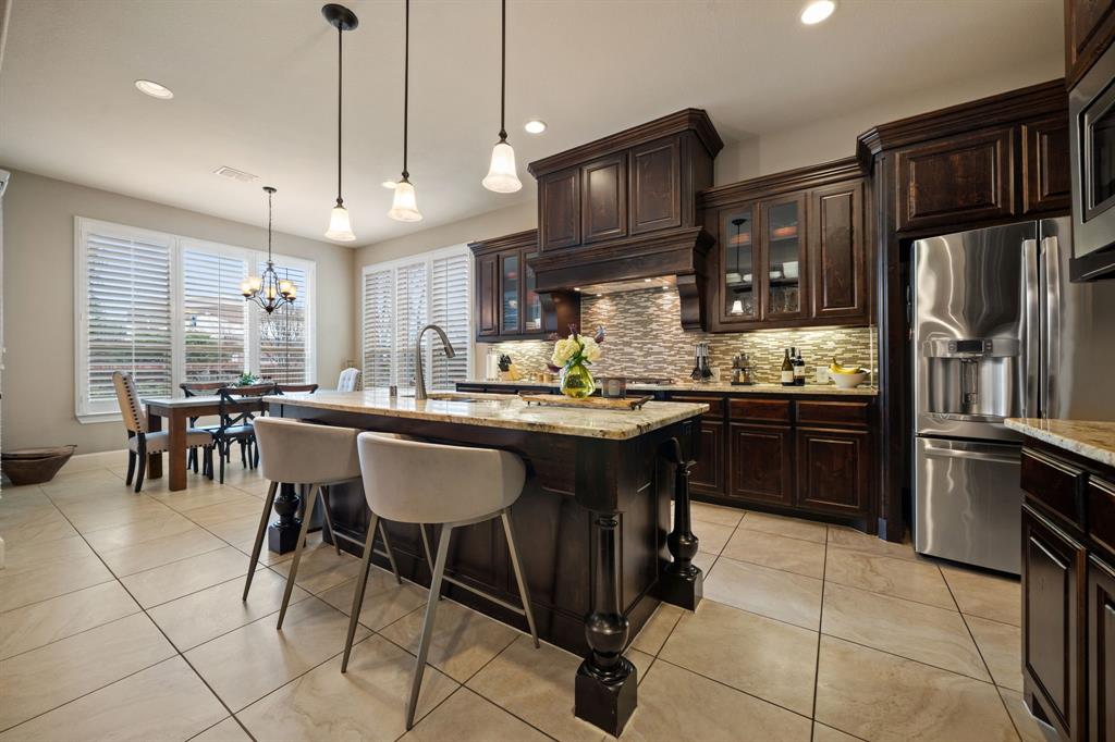 2114 Spicewood Drive Allen, TX 75013 - Photo 11 of 37 a kitchen with stainless steel appliances granite countertop a sink a stove a refrigerator a kitchen island with chairs and cabinets