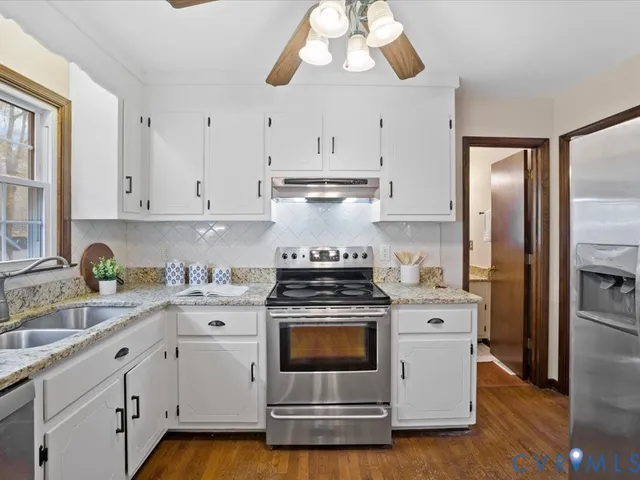 a kitchen with cabinets stainless steel appliances a sink and wooden floor