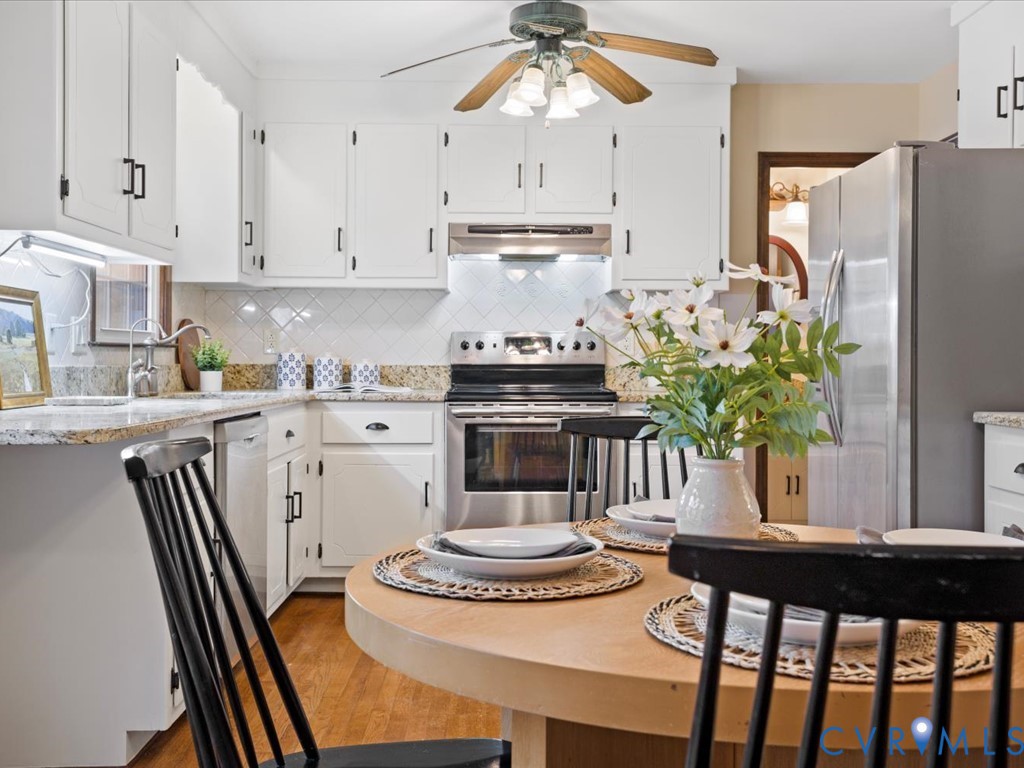 1145 Timber Trace Road Powhatan, VA 23139 - Photo 8 of 32 a kitchen with stainless steel appliances granite countertop a stove a refrigerator a sink a dining table and chairs