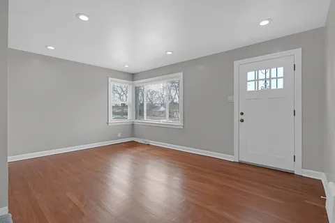 a view of an empty room with wooden floor and windows