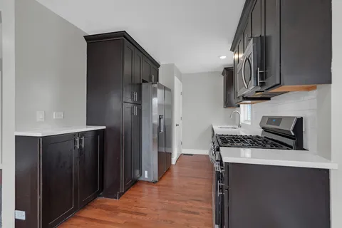 a kitchen with stainless steel appliances granite countertop a refrigerator a stove and a sink with wooden floor