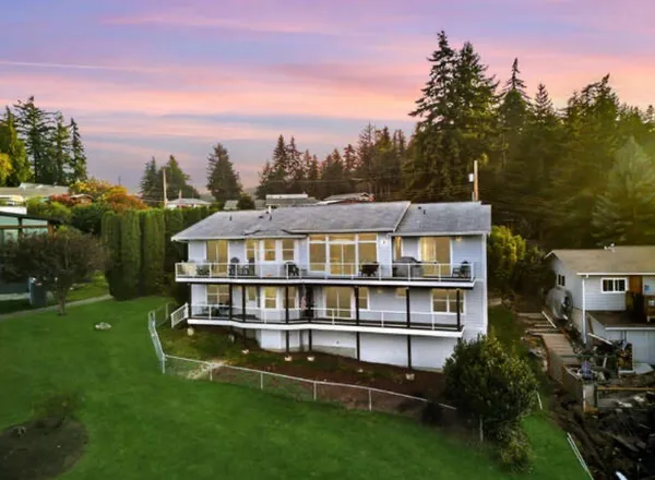 a view of a house with a big yard plants and large trees