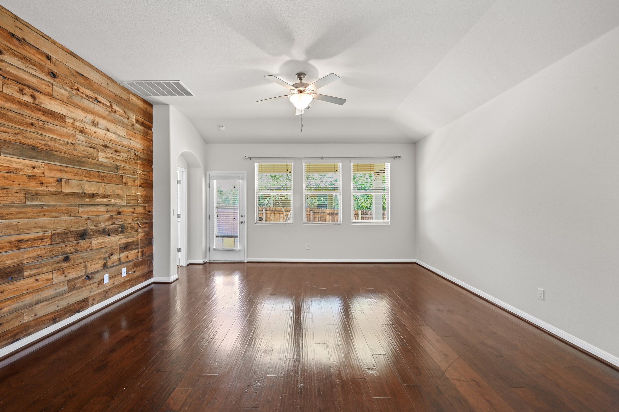 351 Wincliff Drive Buda, TX 78610 - Photo 15 of 40 Refined wood flooring extends across a spacious living area, complemented by a distinctive accent wall.