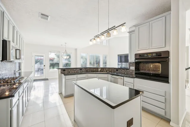 a kitchen with stainless steel appliances granite countertop a stove a sink and a microwave