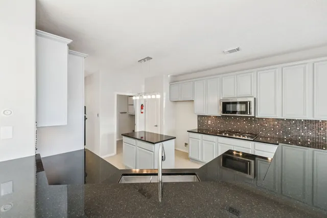 a kitchen with stainless steel appliances kitchen island granite countertop a refrigerator and a stove top oven