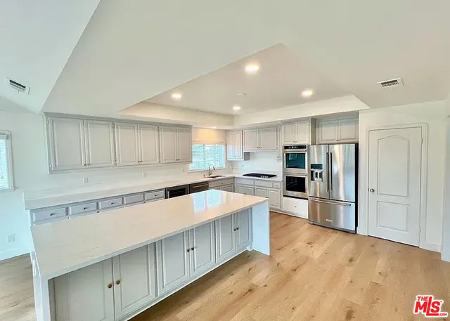a kitchen with stainless steel appliances granite countertop a refrigerator and a stove top oven