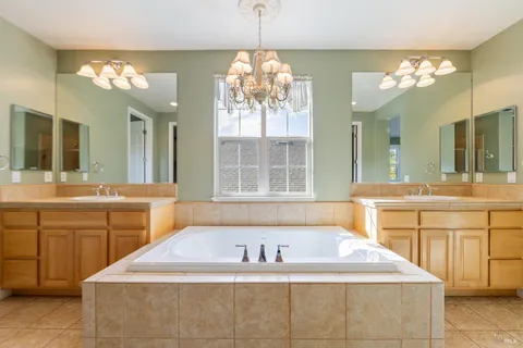 a spacious bathroom with a tub a sink and a large mirror