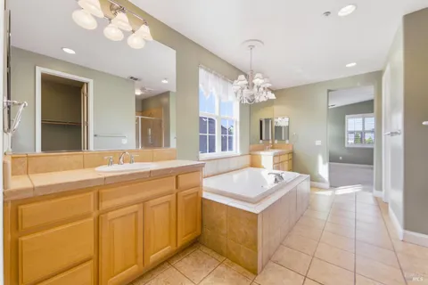 a spacious bathroom with a granite countertop sink a mirror and a bathtub