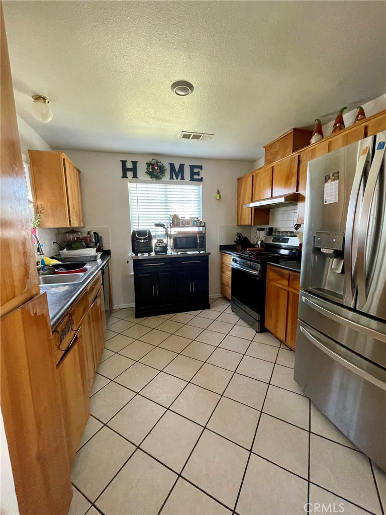 9654 Timothy Court Delhi, CA 95315 - Photo 2 of 18 a kitchen with stainless steel appliances granite countertop a stove top oven a sink a counter space and cabinets