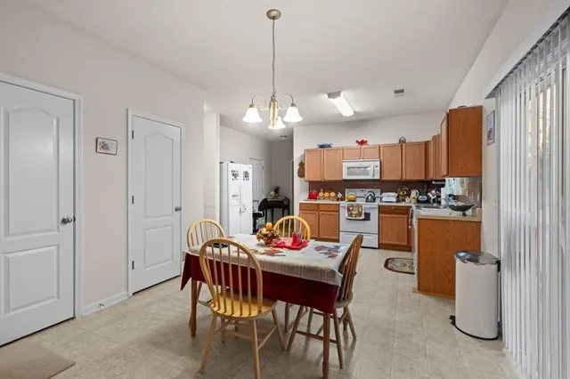 a kitchen with stainless steel appliances kitchen island granite countertop a dining table chairs and a refrigerator