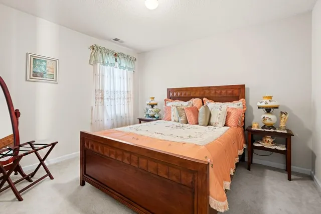 a bed sitting in a bedroom next to a window with a lamp and a large window