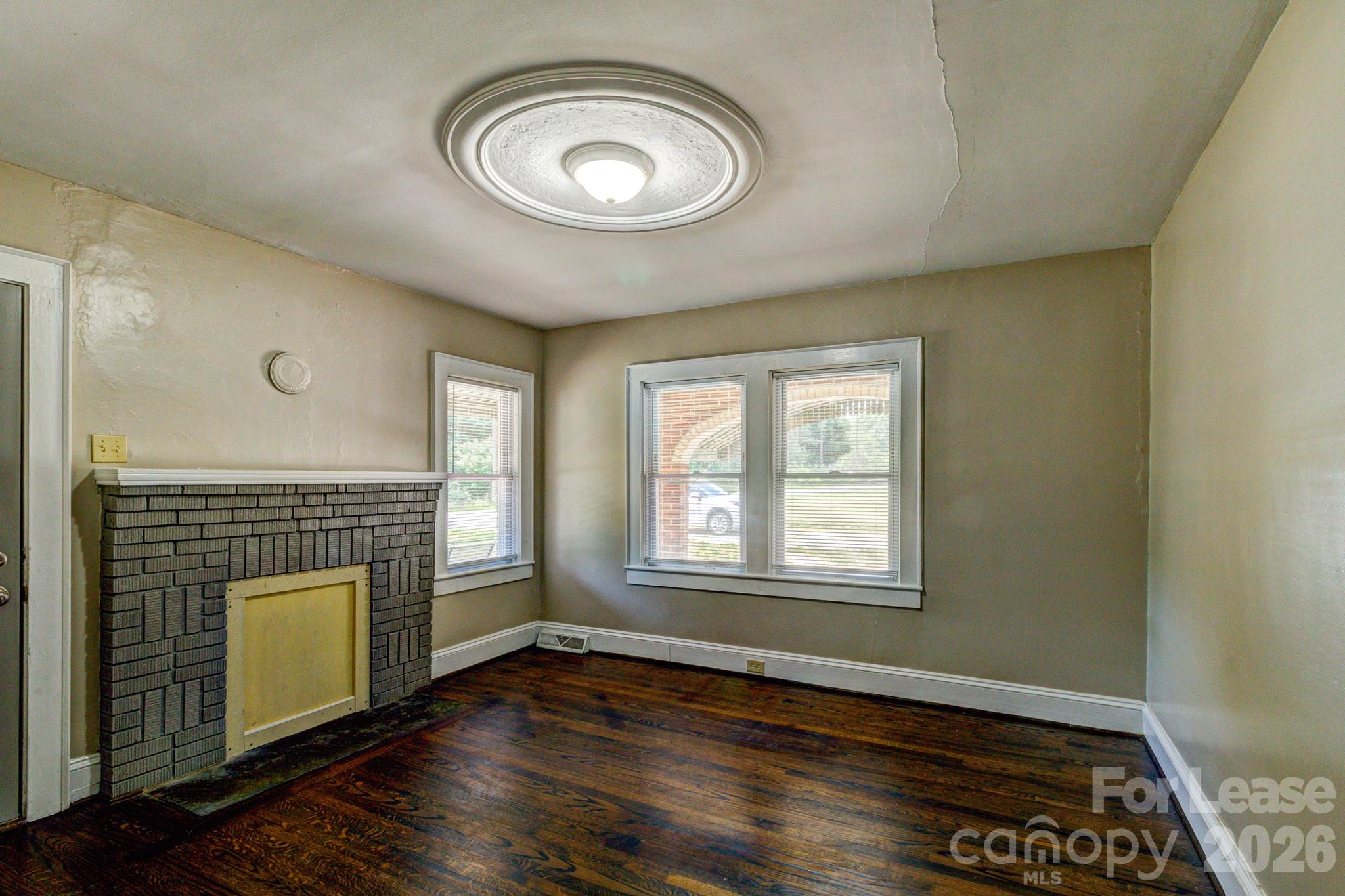 1006 Delview Road Cherryville, NC 28021 - Photo 4 of 10 an empty room with wooden floor a fireplace and windows