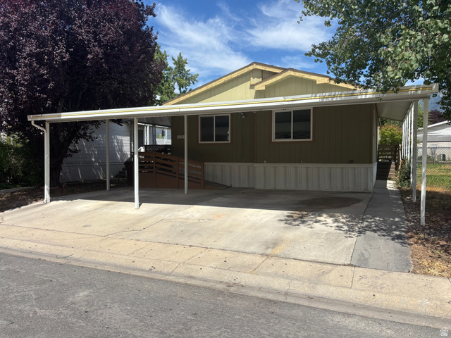11313 South 265 East Sandy, UT 84070 - Photo 5 of 21 Single-story residence featuring an olive green exterior with white trim, a concrete driveway, and an attached white metal carport