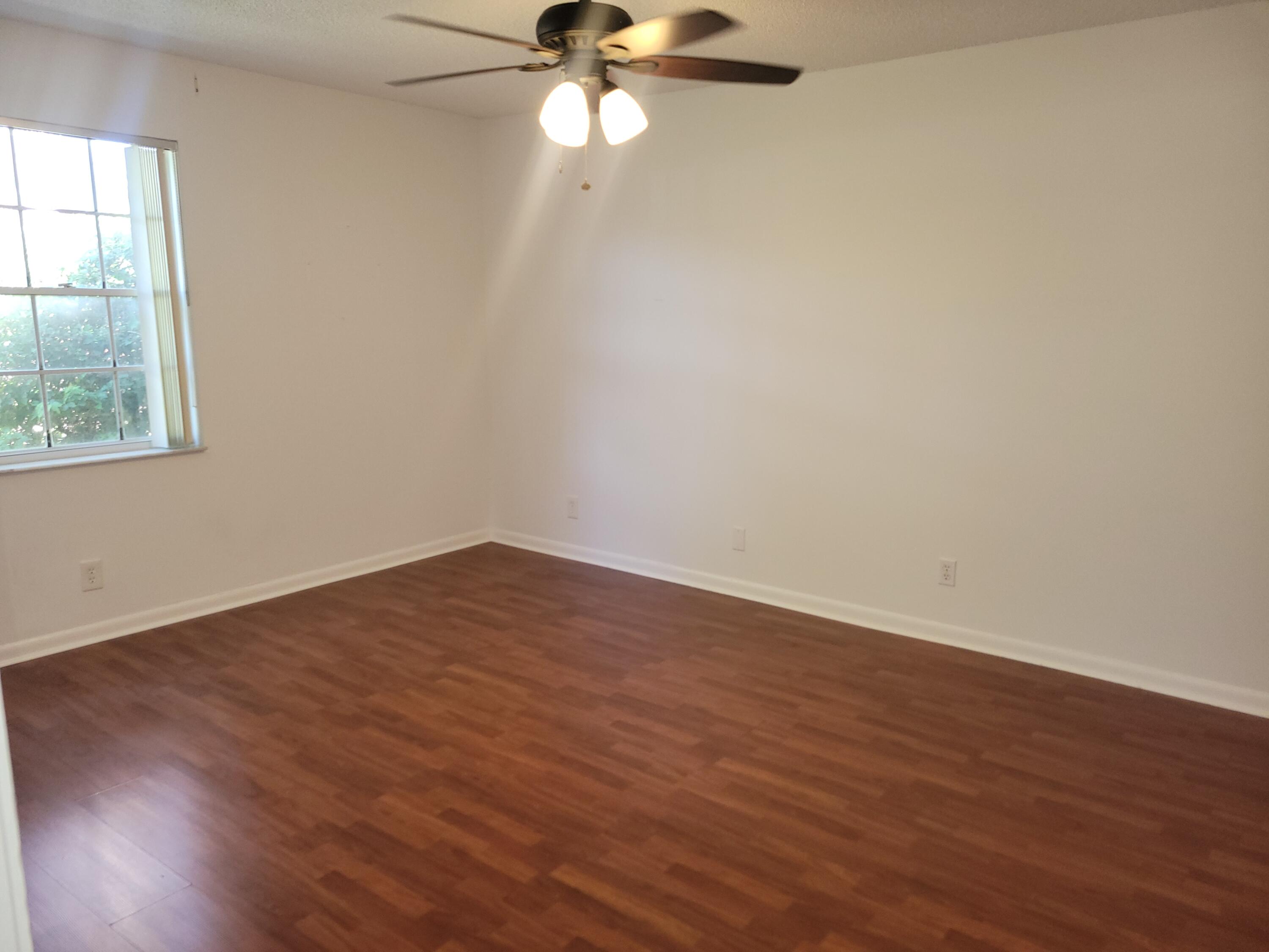 5321 Buckhead Circle, Unit 1020 Boca Raton, FL 33431 - Photo 6 of 13 an empty room with wooden floor fan and windows
