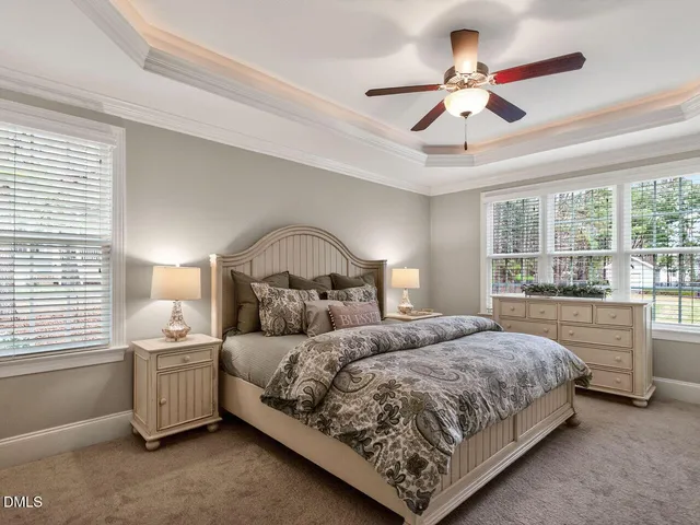 a bedroom with a large bed and a chandelier fan
