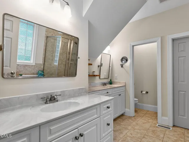 a bathroom with a double vanity sink and mirror with toilet