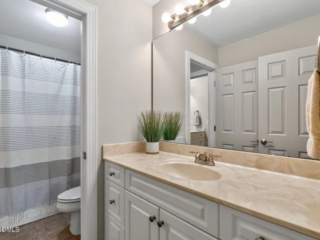 a bathroom with a granite countertop sink a toilet a mirror and shower