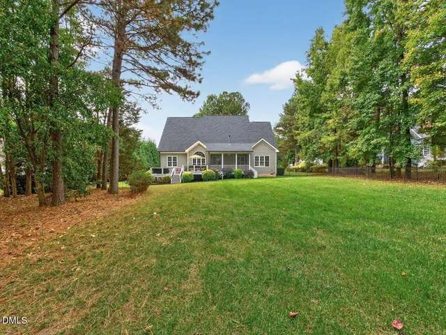 a view of house with garden space and trees in the background