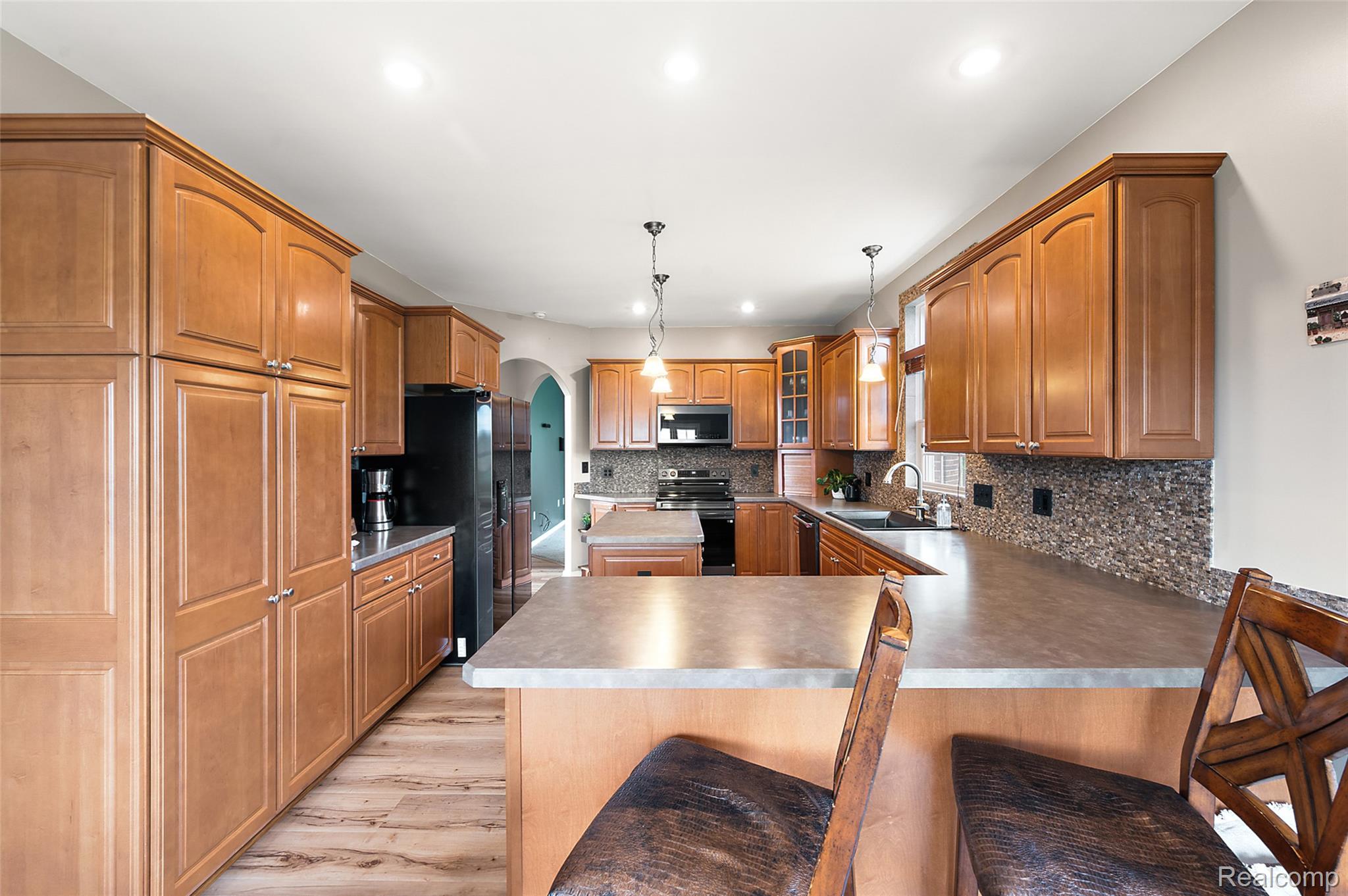 5035 Hidden Ridge Road Metamora, MI 48455 - Photo 22 of 65 Kitchen featuring extensive wood cabinetry, wood-finish flooring, a central island with bar seating, pendant lighting, and recessed ceiling lights
