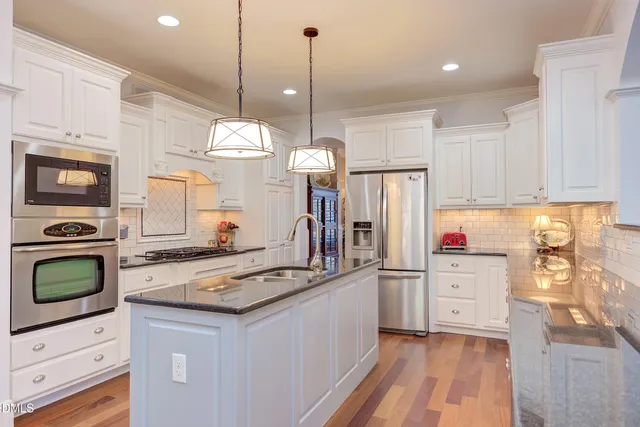 a kitchen with stainless steel appliances granite countertop a sink a stove and a wooden cabinets