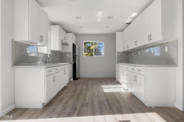 a kitchen with a sink wooden floor and white cabinets