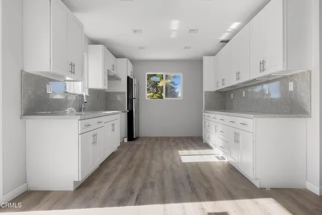 a kitchen with a sink wooden floor and white cabinets