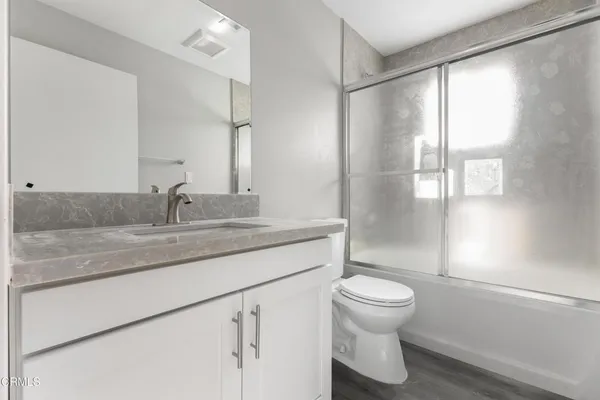 a bathroom with a granite countertop sink a toilet and a large mirror