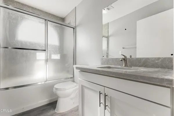 a bathroom with a granite countertop sink a toilet and shower