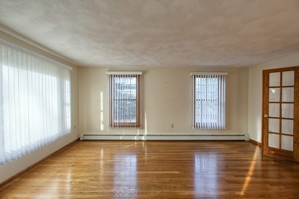 37 Bailey Road Andover, MA 01810 - Photo 12 of 30 an empty room with wooden floor and windows with curtains
