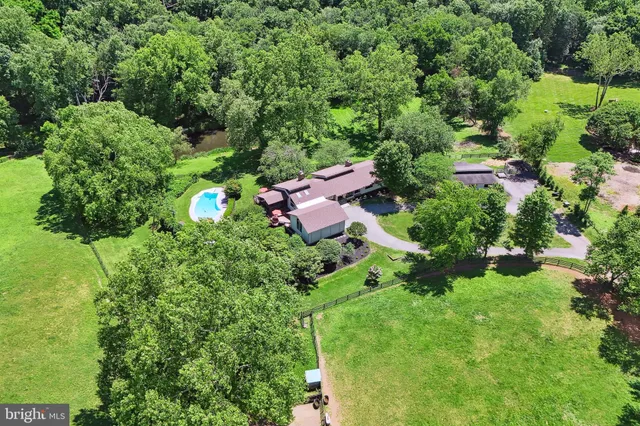 an aerial view of residential house with outdoor space and trees all around