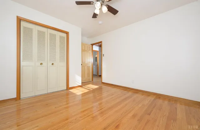 an empty room with wooden floor fan and windows
