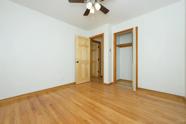 an empty room with a ceiling fan and wooden floor
