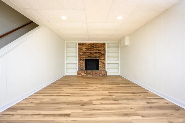 a view of empty room with fireplace and wooden floor