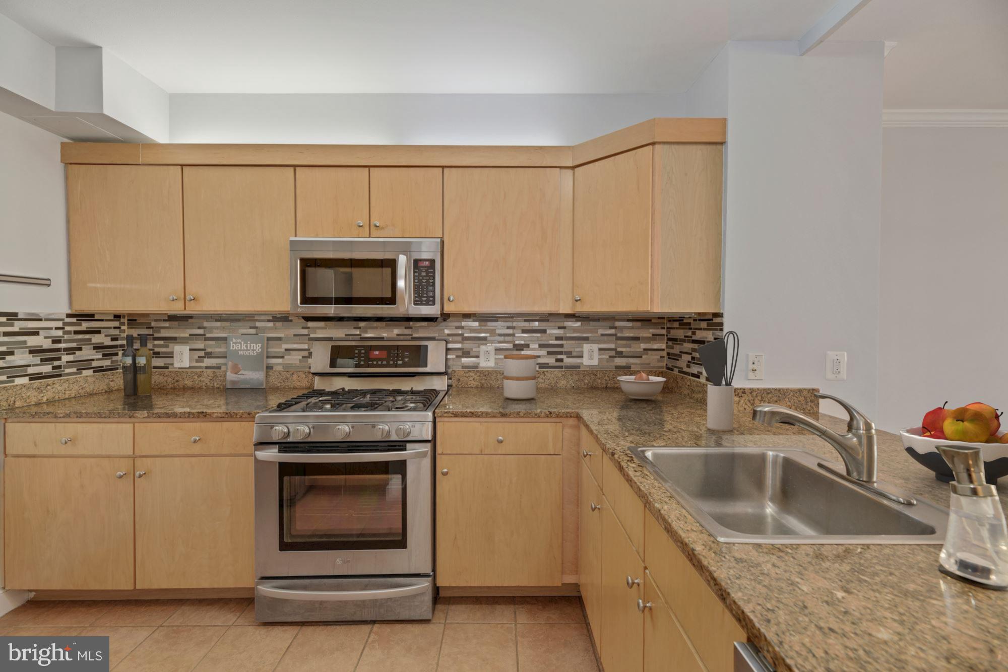 616 E Street Northwest, Unit 1020 Washington, DC 20004 - Photo 7 of 23 a kitchen with granite countertop a sink stove and microwave