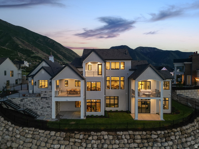 115 East Hidden Ridge Lane, Unit 42 Mapleton, UT 84664 - Photo 87 of 103 Multi-level residence featuring extensive rear balconies and patios, a terraced rock retaining wall, multiple large windows, and a mountain backdrop