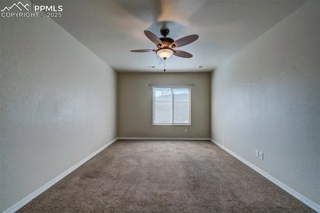 an empty room with a window and a ceiling fan