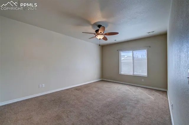 an empty room with windows and chandelier fan