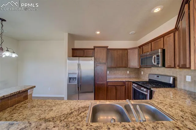 a kitchen with stainless steel appliances granite countertop a sink a stove and a refrigerator