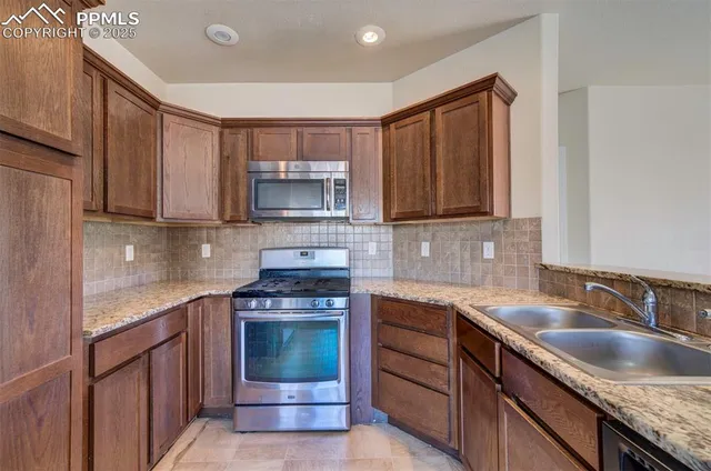 a kitchen with stainless steel appliances granite countertop a sink stove and microwave