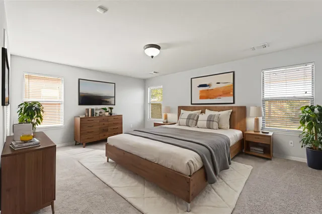 a spacious bedroom with a bed a couch and a potted plant