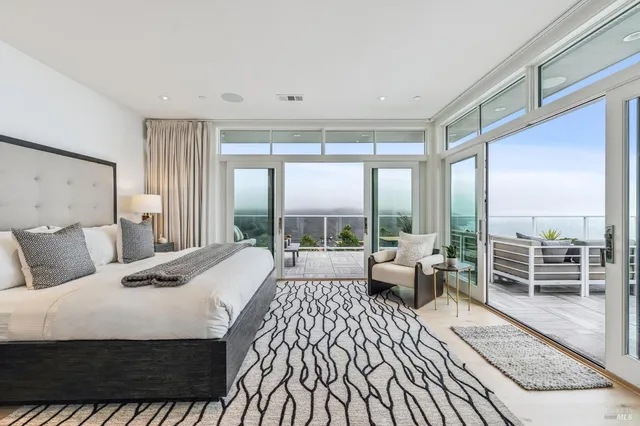 a bedroom with a bed and large windows