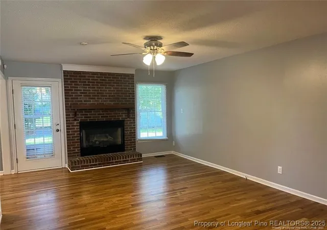 a view of a livingroom with a fireplace wooden floor and fan