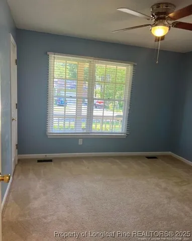 an empty room with windows and chandelier fan